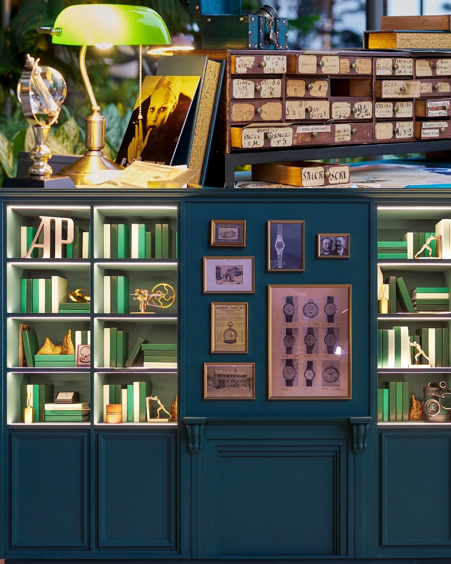 The watchmaker’s library set with green shelves and framed watch drawings