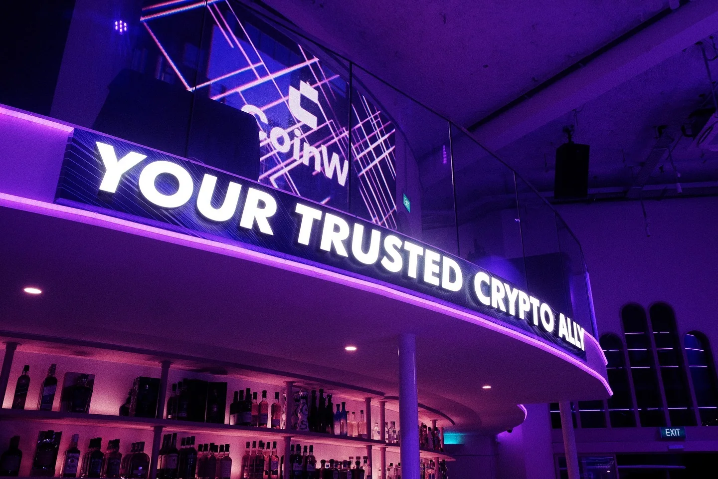 A curved Your trusted crypto ally sign running along the bar