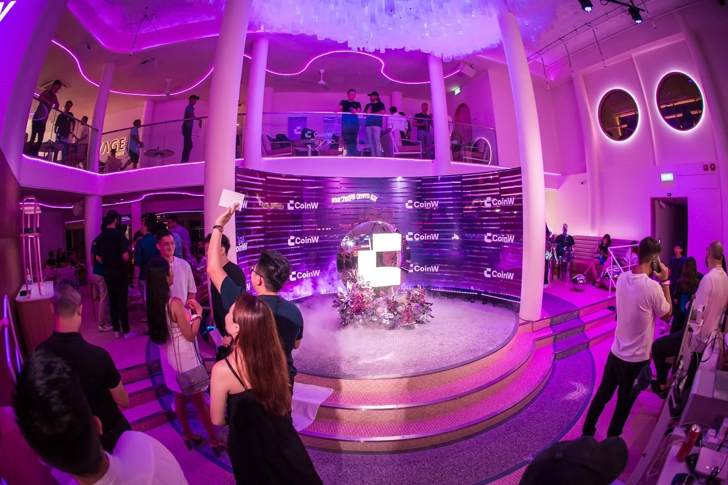 Guests around the CoinW logo installation in the round lounge