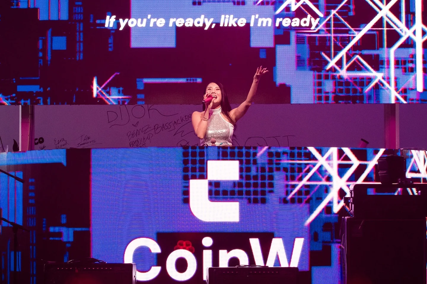 A singer on stage in front of the CoinW screens
